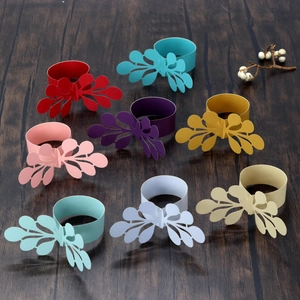 Laser-cut paper napkin rings in eight assorted colors on a dark wooden background
