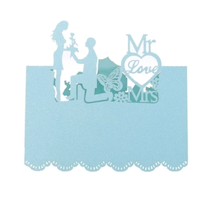 Macro detail of laser-cut light blue wedding seat card with Mr Mrs Love heart patterns