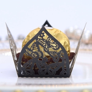 Detail of laser-cut black butterfly chocolate box on white plate with pearl decor