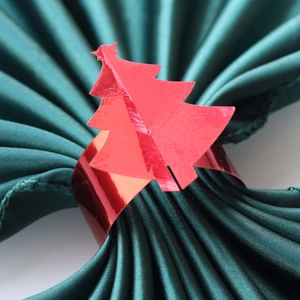 Détail macro du rond de serviette sapin de noël rouge métallique sur satin vert