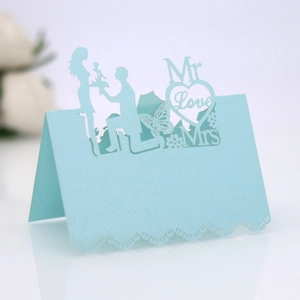 Detail of light blue laser-cut paper place card featuring a romantic wedding silhouette