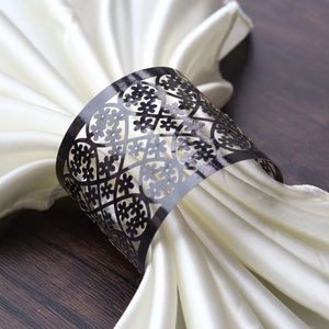 Detailed close-up of a matte black metal napkin ring with laser-cut floral patterns