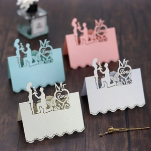 Detail of laser-cut wedding place cards with Mr Love Mrs heart silhouette on pearl paper