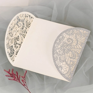 Detail der cremefarbenen Hochzeitseinladung mit silbernem Glitzer-Spitzenmuster und Blume