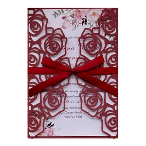 Elegant burgundy laser-cut wedding invitation with rose patterns and red silk ribbon