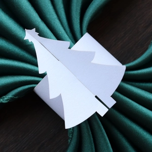 Gros plan d'un rond de serviette blanc en forme de sapin sur tissu vert