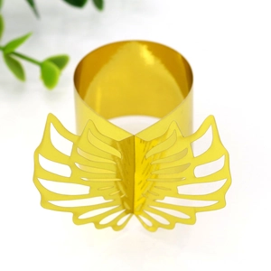 Macro detail of golden metal napkin ring with decorative hollowed-out angel wing design