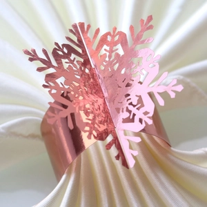 Macro shot of rose gold snowflake napkin ring on elegant cream satin fabric