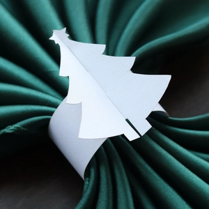 Gros plan d'un rond de serviette sapin de Noël blanc en papier sur tissu vert foncé