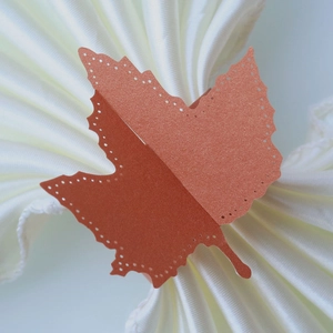 Macro detail of laser-cut maple leaf napkin ring with pearlescent orange finish and hollow dots