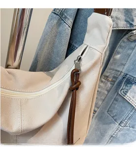Detail eines Metallreißverschlusses mit braunem Lederknoten an einer beigefarbenen Tasche