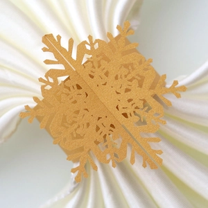 Close-up of gold glitter snowflake paper napkin ring on a white folded table napkin