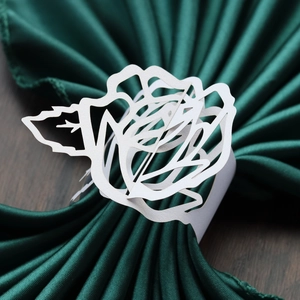 Detailed macro view of laser-cut white paper rose napkin ring for wedding table decor