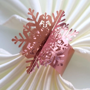 Close-up of snowflake napkin ring in rose gold with elegant cutout metal detailing