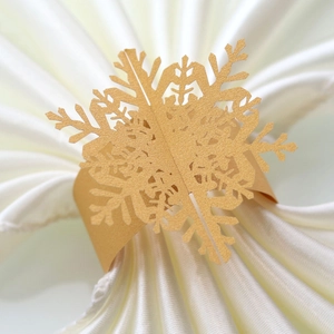 Macro view of gold laser-cut paper snowflake napkin ring on white silk background