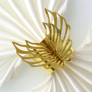 Close-up of golden laser-cut butterfly napkin ring on white satin fabric background