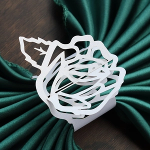 Detail of white laser-cut rose paper napkin ring on a dark silk napkin at 45 degree angle