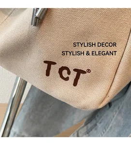 Nahaufnahme der beigen Canvas-Tasche mit gewebter Textur und gesticktem TCT-Logo-Detail