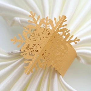 Detailed view of hollow gold pearl paper snowflake napkin ring on a white napkin