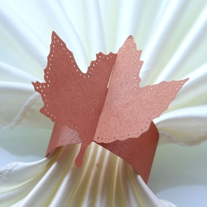 Macro view of laser-cut maple leaf napkin ring in rose gold pearlescent paper