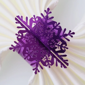 Detailed close-up of a metallic purple snowflake napkin ring on white fabric