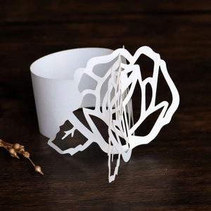 Detail of white laser-cut paper napkin ring with elegant 3D hollow rose design