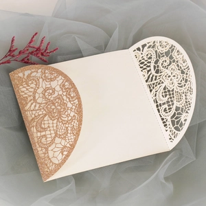 Detail einer lasergeschnittenen Hochzeitseinladung mit roségoldenem Glitzer und Spitze