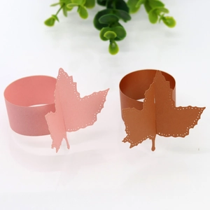 Detail view of laser-cut paper leaf napkin rings in soft pink and bronze metallic finish