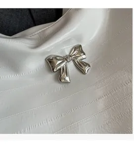 Detail einer weißen Lederhandtasche mit einer polierten silbernen Metallschleife