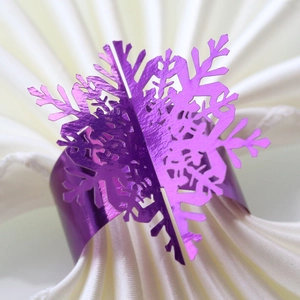 Close-up of shiny purple snowflake napkin ring with metallic mirror finish on white cloth