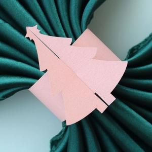 Détail macro d'un rond de serviette sapin de Noël rose sur un tissu en soie vert foncé
