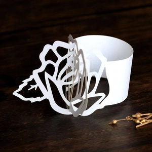 Detailed laser-cut paper napkin ring featuring a white rose design for wedding decor