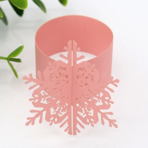 Detailed view of pink pearlescent paper snowflake napkin ring with laser-cut design