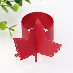 Macro shot of red laser-cut maple leaf paper napkin ring with elegant hollow patterns
