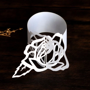 Detailed macro view of laser-cut white rose paper napkin ring on wood surface