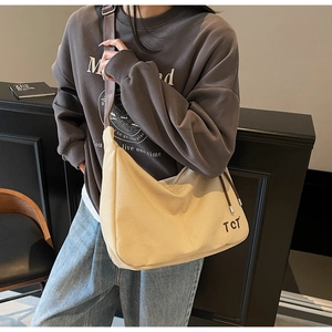 Detail der cremefarbenen Canvas-Tasche mit brauner TCT-Stickerei und Leder-Schultergurt