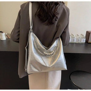 Detail der silbernen Metallic-Tote-Bag mit Perlenkette und strukturierter Oberfläche