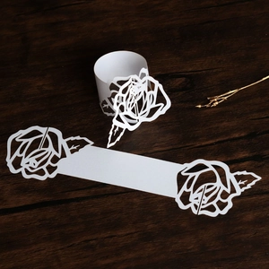Detail of white laser-cut paper napkin rings with elegant hollow rose flower pattern