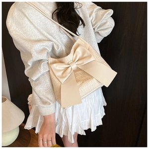 Détail du sac seau en tweed crème avec un grand nœud et un tissu texturé sur le mannequin