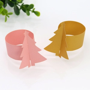 Détail de ronds de serviette sapin de Noël 3D en papier rose et doré sur fond blanc