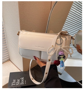 Detailed view of white faux leather bag featuring pearl bow and cute cartoon charms