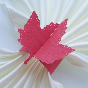 Macro detail of red glitter maple leaf napkin ring with intricate laser-cut hollow dots