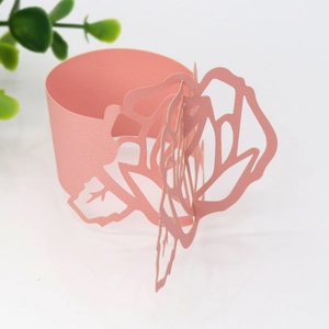 Close-up of laser-cut pink paper napkin rings featuring intricate rose flower designs