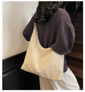 Detail view of large beige nylon tote bag on shoulder for daily commute use