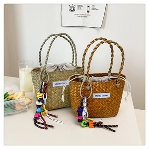 Detail of woven straw tote bags featuring colorful letter beads and drawstring liners