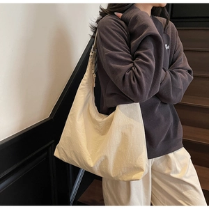 Detailed view of beige nylon hobo bag with adjustable wide strap on model