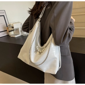Detail der weißen Hobo-Tasche mit Krokodilprägung, Perlen-Schleife und Metallkettenriemen