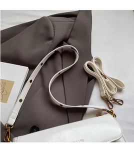 Detail of white glossy leather pillow bag with vintage eyelet shoulder strap and smooth texture