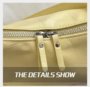 Close-up of dual silver zippers and crocodile pattern texture on a soft leather handbag