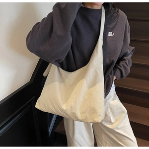 Detail of a large off-white crescent tote bag showing supple nylon texture and wide shoulder strap